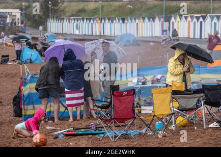 Urlauber trotzen den Elementen am Goodrington North Beach in Paignton, Devon, der von Gewitterschauern getroffen wurde und einige Touristen dazu zwingt, für Deckung zu laufen, Großbritannien. Stockfoto