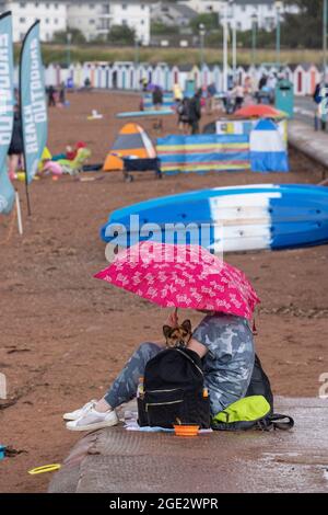 Urlauber trotzen den Elementen am Goodrington North Beach in Paignton, Devon, der von Gewitterschauern getroffen wurde und einige Touristen dazu zwingt, für Deckung zu laufen, Großbritannien. Stockfoto