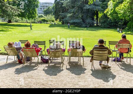 Menschen, die sich in der Sonne auf Stühlen im Jardin du Luxembourg in Paris ausruhen Stockfoto