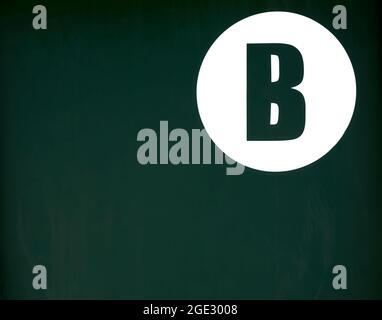 Detail des Buchstaben b in einem weißen Kreis auf einem grünen Metallhintergrund Stockfoto
