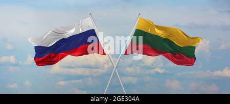 Flaggen von Russland und LITAUEN winken im Wind auf Fahnenmasten gegen den Himmel mit Wolken am sonnigen Tag. Symbolisieren Beziehung, Dialog zwischen zwei Zählen Stockfoto