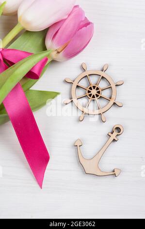 Rote rosa Tulpen mit rotem Band und marineblauem Dekor auf weißem Holzhintergrund und leerem Platz für Text. Draufsicht mit Kopierbereich Stockfoto