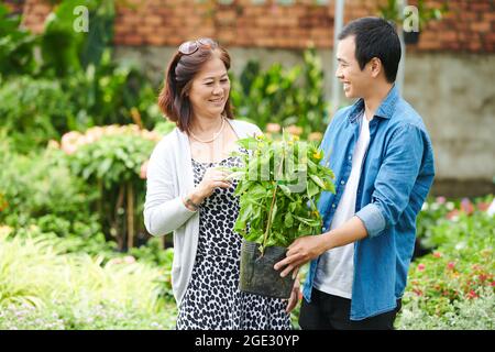 Junger Mann hilft Kunden, die besten Blumen im Gartencenter zu finden Stockfoto