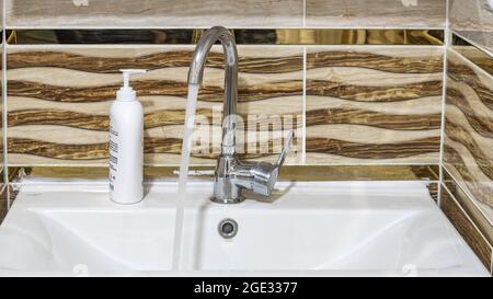 Das Wasser fließt aus einem Metallwasserhahn. Nahaufnahme. Stockfoto
