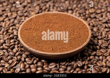 Gemahlener Kaffee in Holzplatte auf Kaffeebohnen Hintergrund Stockfoto