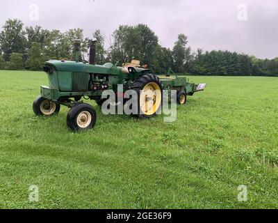 Traktor und Bailer auf dem Feld an einem bewölkten Tag Stockfoto