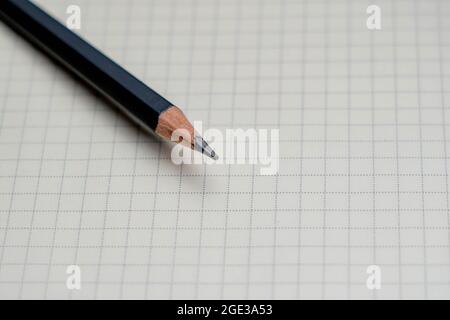 Schwarzer Bleistift und Notizblock auf weißem Hintergrund. Stockfoto