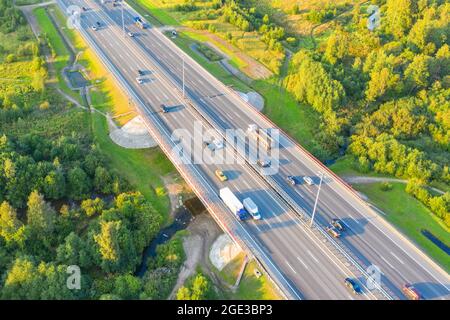 Verkehr auf der Intercity-Autobahn zwischen der natürlichen Parklandschaft. Drone aus der Luft Stockfoto