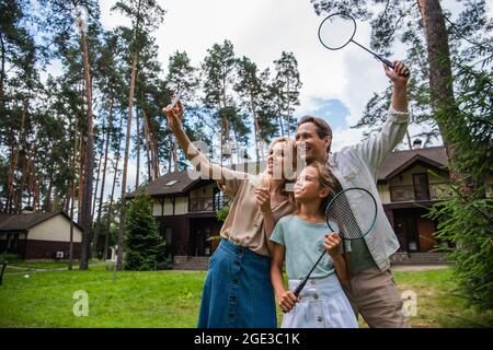Lächelnde Familie mit Badminton-Schlägern, die am Wochenende Selfie auf dem Smartphone machen Stockfoto