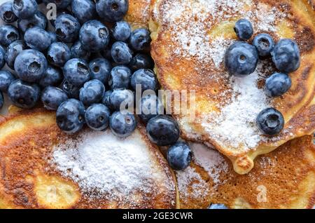 Köstliche hausgemachte Pfannkuchen mit Heidelbeeren und Puderzucker, flache Lay-Ansicht von direkt oben Stockfoto