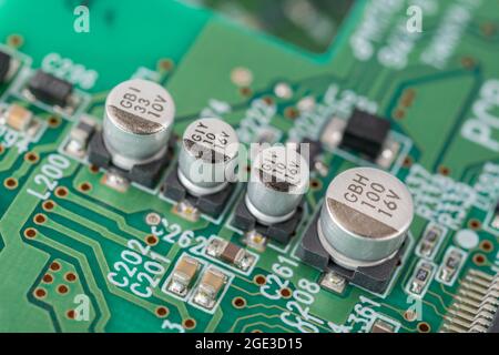 Nahaufnahme einer Reihe solider SMD-V-Chip-Hybrid-Aluminium-Elektrolytkondensatoren auf der leiterplatte mit schwarzer (minus) Polaritätsmarkierung. Marken nicht identifiziert Stockfoto