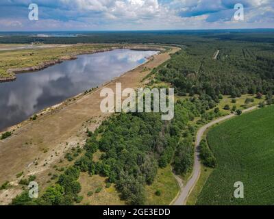 12. Juli 2021, Brandenburg, Cottbus: Der Rand einer ehemaligen Braunkohlegrube und die zukünftige Cottbuser Ostsee (Luftaufnahme mit Drohne). 1986 wurde hier das Dorf Klein Lieskow wegen der Braunkohlengewinnung abgerissen. Klein Lieskow war das 101. Dorf, das vom Kohlebagger verschluckt wurde. Insgesamt verschwanden 137 Häuser im Lausitzer Bergbaugebiet in der Mine. Die Entscheidung, die Kohle bis 2038 auslaufen zu lassen, kommt vielerorts zu spät. (To dpa 'verschwundene Orte in der Lausitz: 'Es gibt Schwermut in der Grube'') Foto: Patrick Pleul/dpa-Zentralbild/dpa Stockfoto