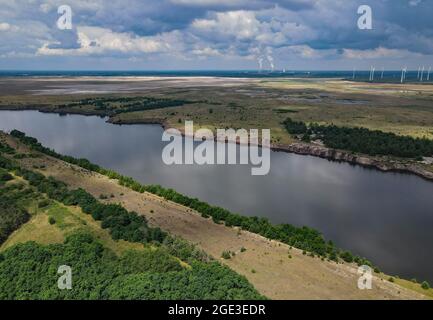 12. Juli 2021, Brandenburg, Cottbus: Der Rand einer ehemaligen Braunkohlegrube und die zukünftige Cottbuser Ostsee (Luftaufnahme mit Drohne). 1986 wurde hier das Dorf Klein Lieskow wegen der Braunkohlengewinnung abgerissen. Klein Lieskow war das 101. Dorf, das vom Kohlebagger verschluckt wurde. Insgesamt verschwanden 137 Häuser im Lausitzer Bergbaugebiet in der Mine. Die Entscheidung, die Kohle bis 2038 zu verlassen, kommt für viele Dörfer zu spät. Foto: Patrick Pleul/dpa-Zentralbild/ZB Stockfoto