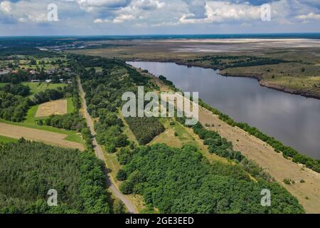 12. Juli 2021, Brandenburg, Cottbus: Der Rand einer ehemaligen Braunkohlegrube und die zukünftige Cottbuser Ostsee (Luftaufnahme mit Drohne). 1986 wurde hier das Dorf Klein Lieskow wegen der Braunkohlengewinnung abgerissen. Klein Lieskow war das 101. Dorf, das vom Kohlebagger verschluckt wurde. Insgesamt verschwanden 137 Häuser im Lausitzer Bergbaugebiet in der Mine. Die Entscheidung, die Kohle bis 2038 zu verlassen, kommt für viele Dörfer zu spät. Foto: Patrick Pleul/dpa-Zentralbild/ZB Stockfoto