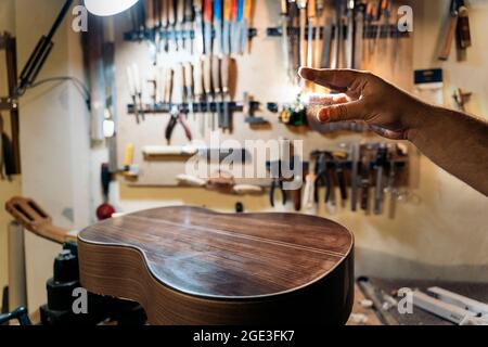 Unbekannter Geigenbauer, der in seiner Werkstatt eine Gitarre kreiert und Werkzeuge verwendet. Stockfoto
