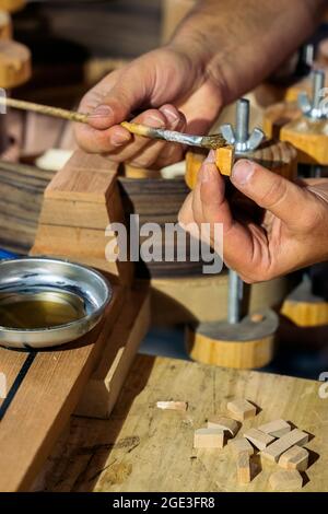Unbekannter Geigenbauer, der eine Gitarre kreiert und Werkzeuge in einer traditionellen Werkstatt verwendet. Stockfoto