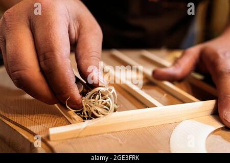Unbekannter Geigenbauer, der eine Gitarre kreiert und Werkzeuge in einer traditionellen Werkstatt verwendet. Stockfoto