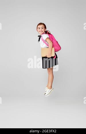 Nette glücklich Schulmädchen springen mit Rucksack Stockfoto