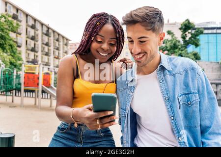 Multiethnische junge Freunde nutzen ihr Telefon in der Stadt und haben Spaß. Stockfoto