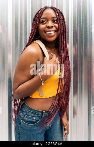 Schöne junge afrikanische Frau mit Zöpfen, die draußen nach vorne schauen und lächeln. Stockfoto