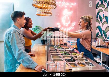 afroamerikanische Frau und ihre Freundin kaufen in einem coolen Restaurant eine Poke-Schale. Stockfoto