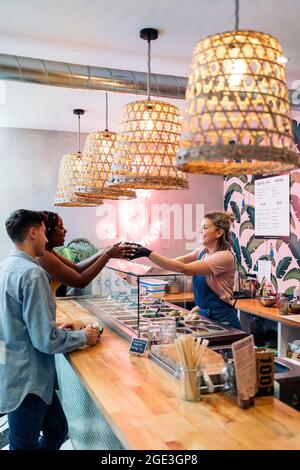 afroamerikanische Frau und ihre Freundin kaufen in einem coolen Restaurant eine Poke-Schale. Stockfoto