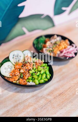 Nahaufnahme von köstlichen und gesunden Poke-Schüsseln mit Lachs und Gemüse, die in einem Restaurant serviert werden. Stockfoto