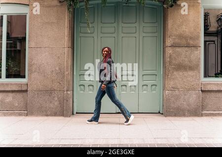 Schöne junge afrikanische Frau mit Zöpfen lächeln und gehen auf der Straße. Stockfoto