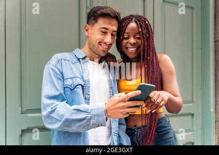 Multikulturelle junge Freunde, die in der Stadt telefonieren und Spaß haben. Stockfoto
