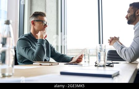 Serious Geschäftsmann Arbeitgeber hr hält cv hören Bewerber bei Vorstellungsgespräch. Stockfoto