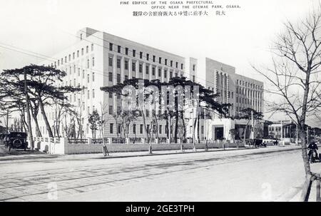 Alte japanische Schwarz-Weiß-Postkarte, ca. 1930 des sechsstöckigen Steingebäudes des Präfekturbüros von Osaka. Straße im Vordergrund mit Straßenbahnlinien Stockfoto