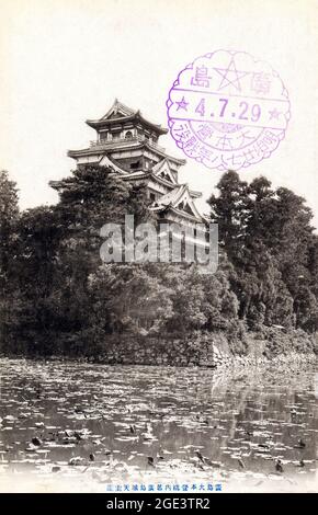 Alte, schwarz-weiße japanische Postkarte der Burg Hiroshima und der mit Seerosen gefüllte Graben mit einem Poststempel auf der Vorderseite, der die Karte auf das Jahr 1929 datiert. Stockfoto