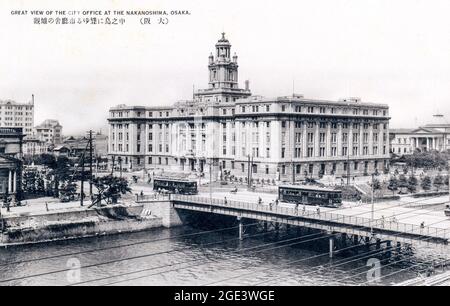 Alte japanische Schwarz-Weiß-Postkarte, um 1930, vom Osaka City Office, Rathaus in Nakanoshima, in Osaka. Gebäude am Fluss mit Brücke. Stockfoto