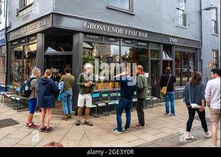 Kunden, die vor dem berühmten Grosvenor Fish and Chip Shop in der Lower Goat Lane Norwich auf die Bestellung warten Stockfoto