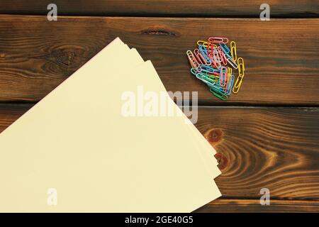 Büroklammern und Papier auf Holzhintergrund Stockfoto