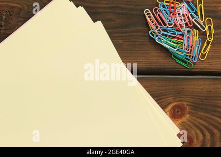 Büroklammern und Papier auf Holzhintergrund Stockfoto