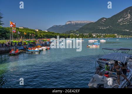 Sommerspaß an einem Sommertag am See von Annecy. Touristen auf Tretbooten und unter Sonnenschirmen. Annecy, Département Savoie, Region Auvergne-Rhône-Alpes, Frankreich Stockfoto