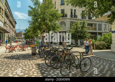 Touristen schlendern auf der Rue de la République in Grenoble. Fahrräder, die an einem sonnigen Sommertag im Schatten geparkt sind. Grenoble, Frankreich Stockfoto