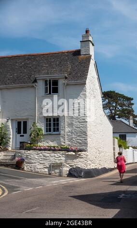 St Mawes, Cornwall, England, Großbritannien. 2021. Urlauber, die an einem weiß getünchten Häuschen im Dorfzentrum von St. Mawes im Süden von Cornwall vorbeischlendern. Stockfoto