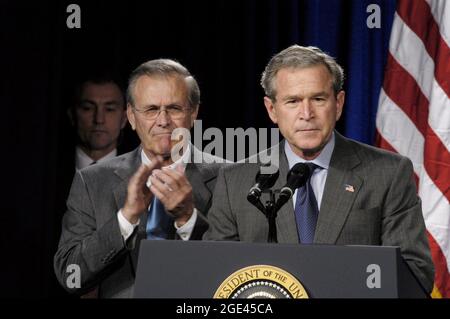 WASHINGTON DC, USA - 24. November 2003 - US-Verteidigungsminister Donald H. Rumsfeld applaudiert Präsident George W. Bush während seiner Ausführungen im Pentagon. Stockfoto