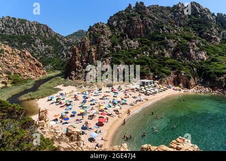 Menschen und Sonnenschirme am Strand von Li Cossi an der Costa Paradiso von Sardinien, Italien Stockfoto