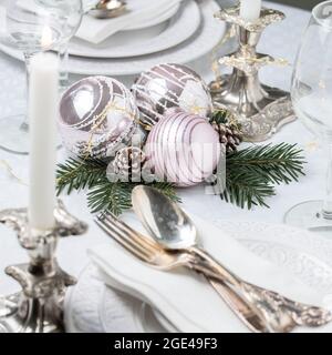 Weihnachtliche Tischkulisse mit weißen Servietten, antikem Splitterbesteck und Kerzenhaltern Stockfoto