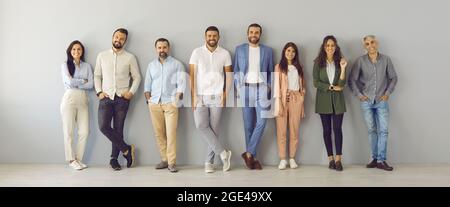Porträt eines Teams aus Männern und Frauen unterschiedlichen Alters, das in einer Reihe in der Nähe der Wand steht. Stockfoto