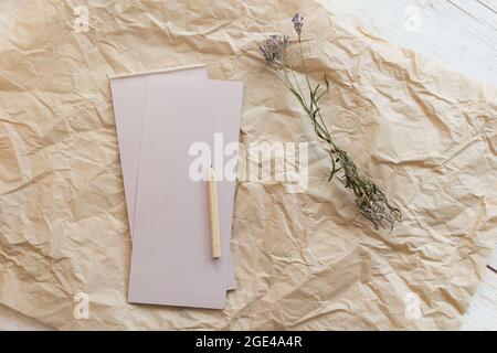 Flache Lay-Komposition mit einem Tränenkraftpapier-Notizblock, Bleistift und getrocknetem Lavendel auf einem Kraftpapier-Hintergrund. Draufsicht. Stockfoto