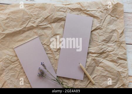 Flache Lay-Komposition mit einem Tränenkraftpapier-Notizblock, Bleistift und getrocknetem Lavendel auf einem Kraftpapier-Hintergrund. Draufsicht. Stockfoto