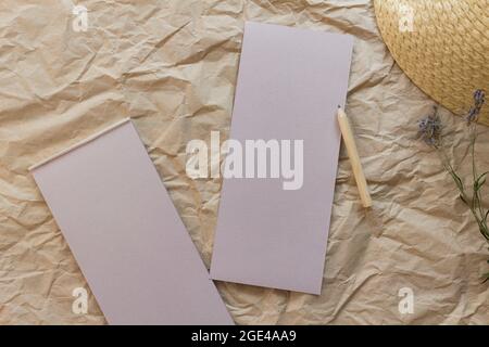 Flache Lay-Komposition mit einem Tränenkraftpapier-Notizblock, Bleistift, getrocknetem Lavendel und Strohhut auf einem Kraftpapier-Hintergrund. Draufsicht. Stockfoto