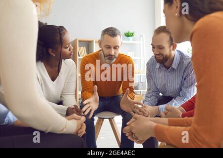 Professioneller Therapeut, der während einer Gruppentherapie mit verschiedenen Patienten spricht Stockfoto