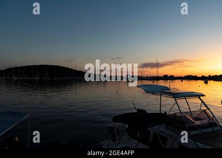 Rogoznica, Kroatien-8. Juli 2021: Schöner, goldener Sonnenuntergang über der touristischen Stadt Rogoznica an der dalmatinischen Küste Kroatiens, oberhalb des Stadthafens mit anc Stockfoto