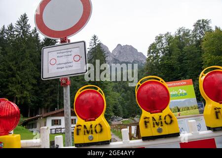 Grainau, Deutschland. August 2021. Nach einer Überschwemmung in der Höllentalklamm steht auf der Zufahrtsstraße ein Hinweisschild. Am Fuße der Zugspitze liegt die Höllentalklamm, eine beliebte Schlucht für Wanderer. Am Montag, den 16. August 2021, rauscht plötzlich eine Flutwelle durch die Schlucht. Mehrere Personen werden vermisst. Kredit: Peter Kneffel/dpa/Alamy Live Nachrichten Stockfoto