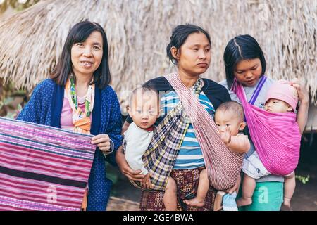 LAMPHUN THAILAND - 8. Dezember: Nicht identifizierte weibliche Touristen ein Bild mit Karen Familie auf Dezember 8,2019 bei Karen Dorf in Lamphun, Thailand Stockfoto